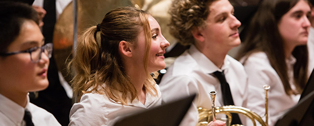 Students smile from the brass section of the Delaware Youth Symphony Orchestra